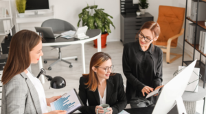 Image of three women around a computer talking about moving from an accounting to fintech career